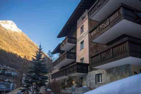 Zermatt Village Residence with mountain backdrop and wooden balconies.