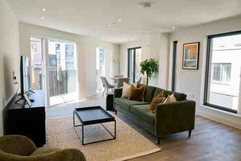 Spacious living room with large windows, stylish furniture, and natural light in King's Cross Apartm.