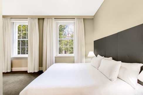 Bright hotel room with large windows and white bedding in Adelaide.