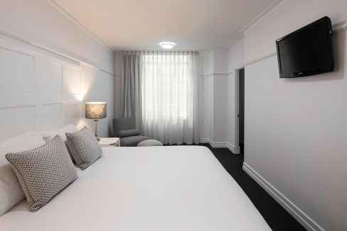 Modern Brisbane Central Aparthotel room with bed, TV, and seating area.