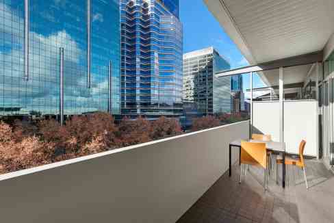 Balcony view of Perth Exhibition Centre Aparthotel with city skyscrapers and blue sky.