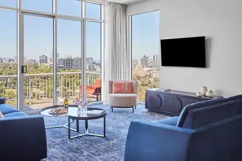 Bright living room with city views at Melbourne Flinders Street Aparthotel.