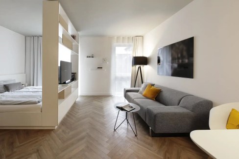 Bright living room in Munich apartment with sofa, TV, and natural light.
