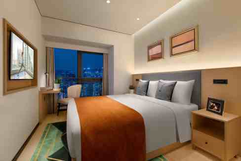 Modern hotel room with a large bed, city view, and contemporary decor.