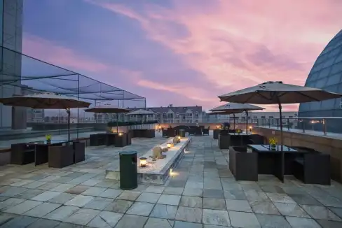 Rooftop terrace at Dalian Grand Central Aparthotel with outdoor seating and sunset view.