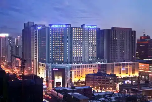 Aparthotel at Shenyang Railway Station with modern high-rise buildings and city lights.