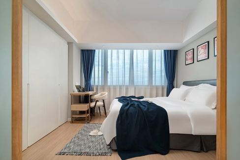 Hotel room at Shanghai Yan’an Road Aparthotel with cozy bedding and contemporary design.