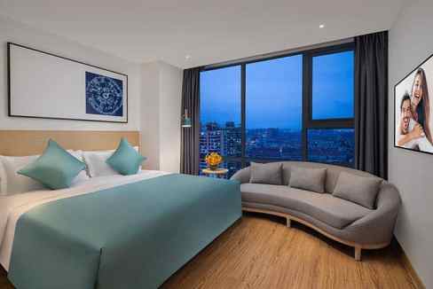 Hotel room with city skyline view, contemporary decor, and comfortable seating at Nantong Changbeicu.