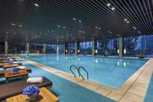 Indoor swimming pool with clear water and relaxing lounge area at Nanjing Youth Olympic Aparthotel.