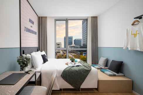 Comfortable hotel room with large window overlooking Shanghai skyline and urban landscape.