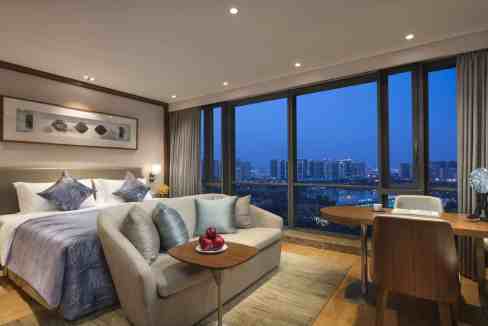 Modern living room with large windows overlooking Suzhou skyline.