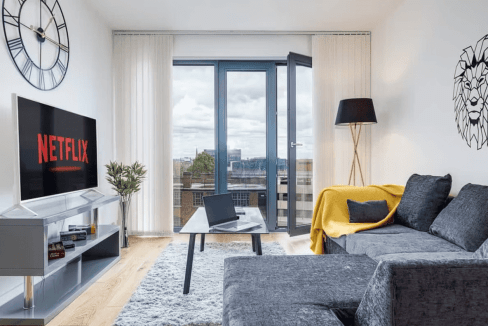Modern Birmingham apartment living room with balcony view, Netflix on TV, and stylish decor.