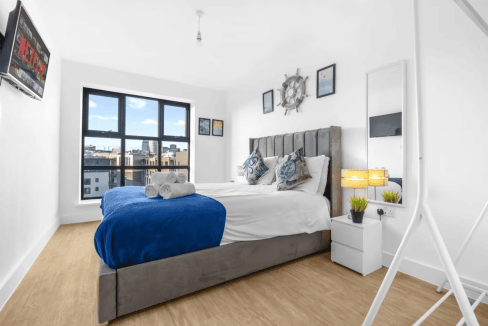 Bright bedroom featuring large windows, stylish furnishings, and seaside-inspired accents.