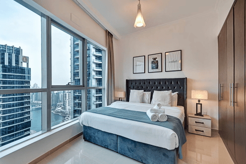 Modern bedroom in Dubai Bay Central Apartments with large windows and city skyline view.