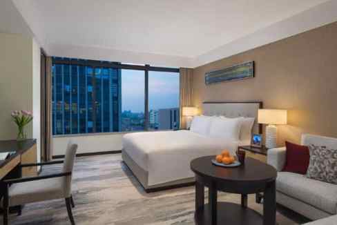Modern hotel room with city skyline view at Hangzhou Huanglong Stadium Aparthotel, featuring a comfo.