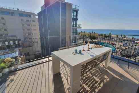 Balcony with outdoor table overlooking city and ocean at Daniel Street Apartments.