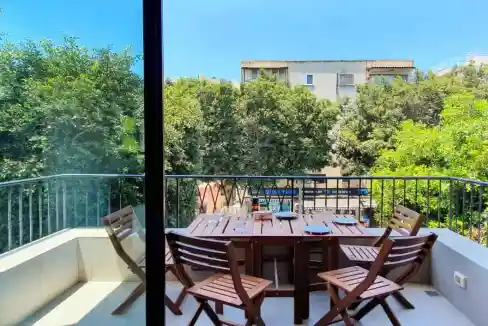 Balcony overlooking lush greenery and neighboring buildings at Dizengoff Street Apartments.