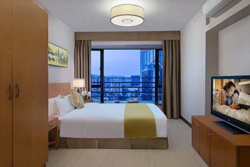 Modern hotel room at Guangzhou Tianhe Gymnasium Aparthotel with city skyline view.
