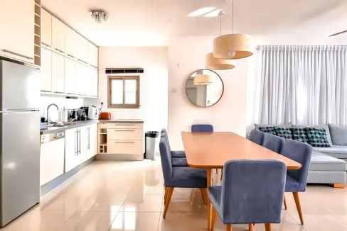 Bright, spacious living room with modern decor and open kitchen in HaRav Kook Street Apartments.