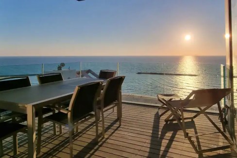 Seaside balcony overlooking the ocean with outdoor dining table and lounge chairs, perfect for enjoy.