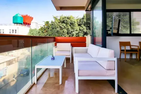Balcony with white seating and cityscape view at Kalischer Street Apartments.