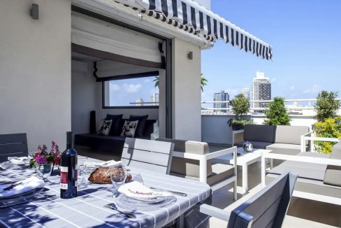 Rooftop terrace at Melchett Street Apartments featuring outdoor seating and city skyline views.