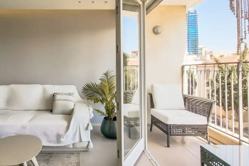 Balcony of Pines Street Apartments with outdoor seating and cityscape background.