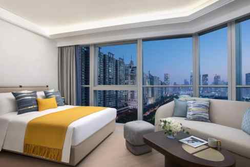 A spacious hotel room at Guangzhou Tianhe Road Aparthotel featuring large windows with a cityscape v.