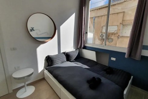 Bright bedroom with large window and minimalist decor at Yosef Eliyahu Apartments.