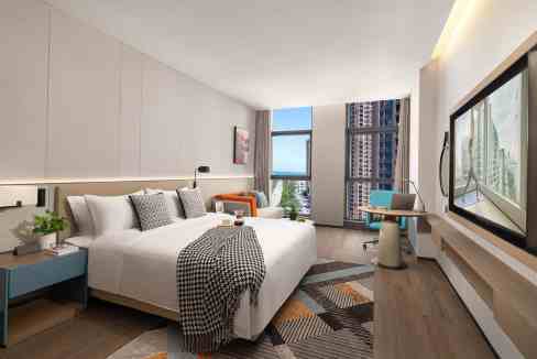 Spacious hotel room at Yantai Jinqiao Aparthotel featuring modern furnishings and city skyline views.
