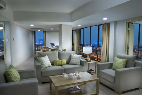 Spacious living room featuring large windows with cityscape views, comfortable sofas, and elegant de.