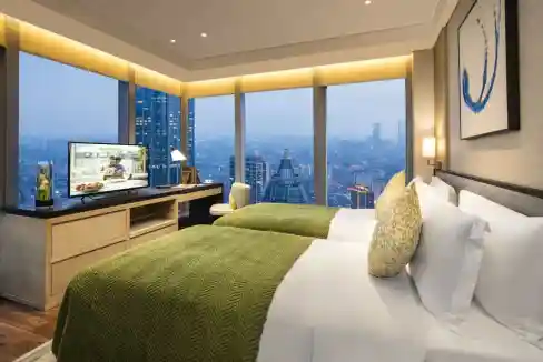 Luxurious hotel room featuring a large bed, panoramic city views, and contemporary decor at Wuxi Gon.