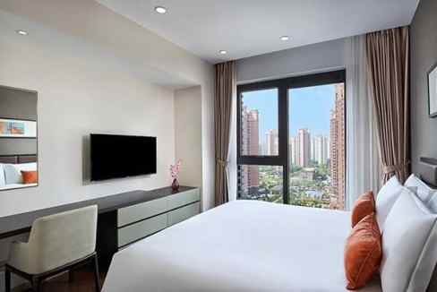 Aparthotel room at Yangzhou Yangzhuang River with large window overlooking city skyline.