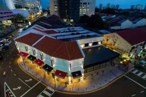 Apt hotel in Penang with modern architecture and vibrant lighting, situated in a lively urban area.