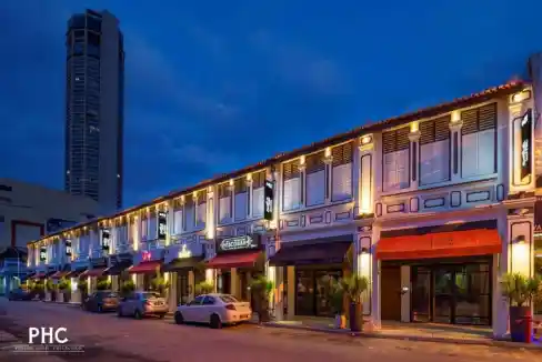 Aparthotel building near Komtar Bus Terminal with illuminated facade and parked cars.