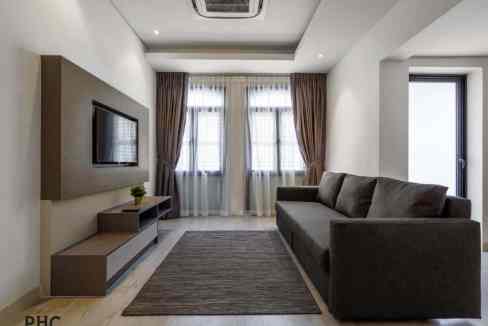 Comfortable living space featuring a sofa, flat-screen TV, and large windows at Penang Macallum Apar.