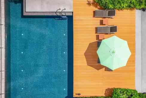 Pool and sun deck at Bangkok Sukhumvit 24 Aparthotel with lounge chairs and umbrella.
