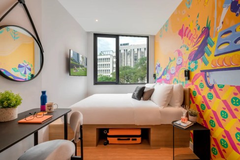 Bright, contemporary hotel room with vibrant mural wall and large window in Kuala Lumpur Menara Apar.