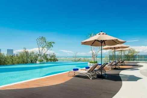 Poolside view at Penang Gurney Bay Aparthotel with lounge chairs and umbrellas.