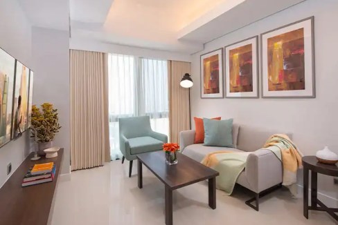 Aparthotel living room in Manila Makati with contemporary furniture, colorful artwork, and natural l.