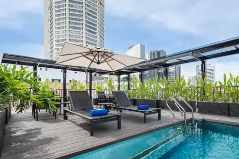 Relaxing rooftop pool with sun loungers, umbrellas, and city views at Penang Theme Park Aparthotel.