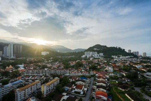 Panoramic view of Penang Tanjung Tokong with cityscape and mountains at sunset.