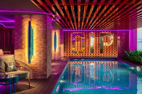 Indoor pool at Penang Georgetown Aparthotel featuring vibrant neon lights and modern decor.