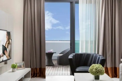 Aptly titled Kuching Uplands Aparthotel, this modern room features a balcony with outdoor seating an.