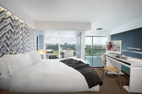 Modern hotel room with a large bed and city view in Fusionopolis Way, Singapore.