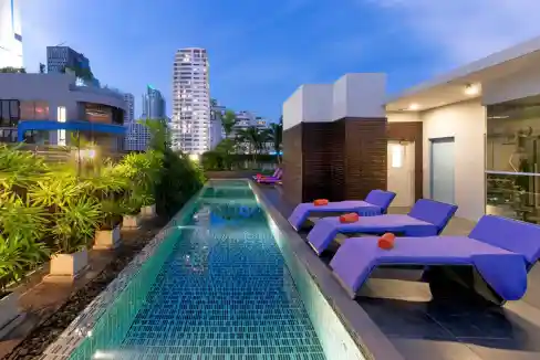 Rooftop pool at Bangkok Sukhumvit 11 Aparthotel with city skyline backdrop.