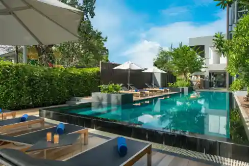 Outdoor swimming pool with lounge chairs and umbrellas at Bangkok Thanon Ekkamai Aparthotel.