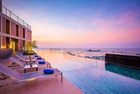 Sunset view from the infinity pool at Sri Racha Harbourview Aparthotel, showcasing a tranquil seasid.