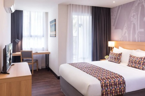 Modern Binh Duong Aparthotel room featuring a cozy bed, workspace, and natural light for a relaxing.