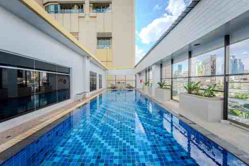 Rooftop pool at Bangkok Sukhumvit 16 Aparthotel with city skyline view.